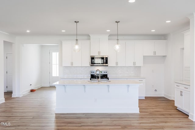 kitchen featuring sink, hanging light fixtures, an island with sink, light hardwood / wood-style floors, and stainless steel appliances