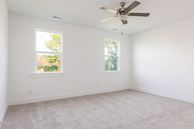 carpeted spare room with a wealth of natural light and ceiling fan