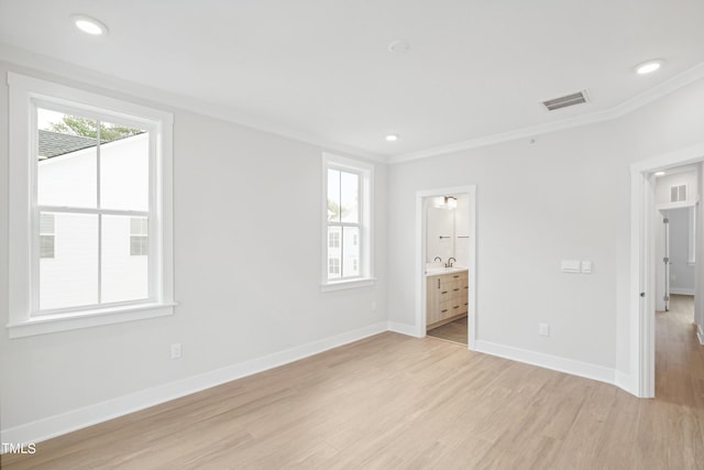 unfurnished bedroom featuring light wood-type flooring, connected bathroom, and crown molding