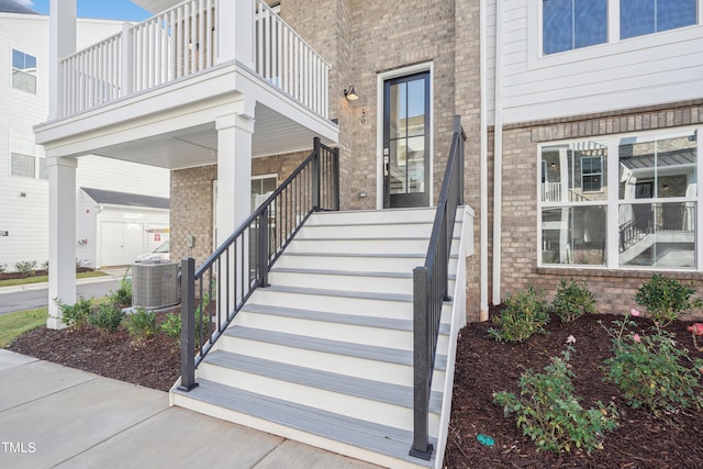 view of exterior entry featuring cooling unit and a balcony