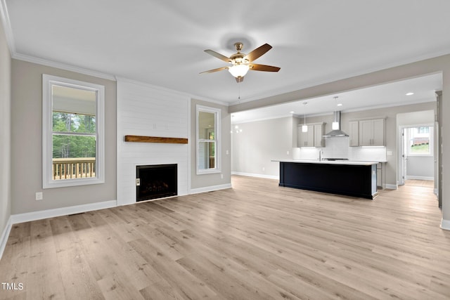 unfurnished living room featuring ceiling fan, light hardwood / wood-style flooring, a large fireplace, and a healthy amount of sunlight