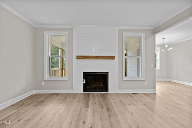 unfurnished living room featuring crown molding, a notable chandelier, light hardwood / wood-style flooring, and a fireplace