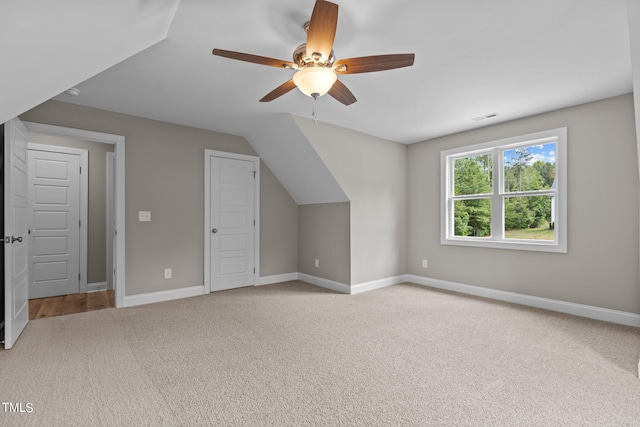 additional living space with ceiling fan, vaulted ceiling, and light carpet