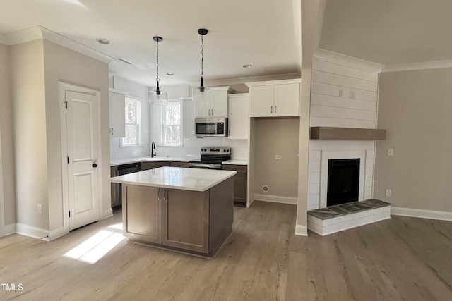 kitchen with light hardwood / wood-style flooring, white cabinetry, hanging light fixtures, stainless steel appliances, and a kitchen island