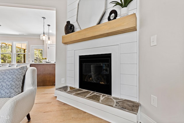 living area with light wood-type flooring and a glass covered fireplace