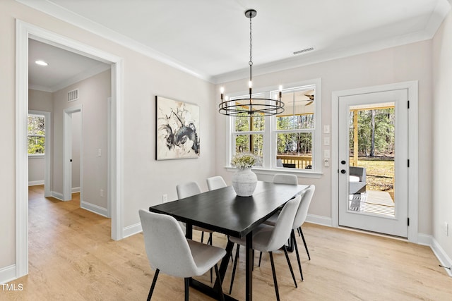 dining area with baseboards, visible vents, light wood-style flooring, crown molding, and a chandelier