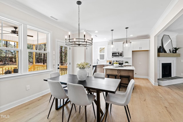 dining room with a healthy amount of sunlight, light wood-style flooring, visible vents, and ornamental molding