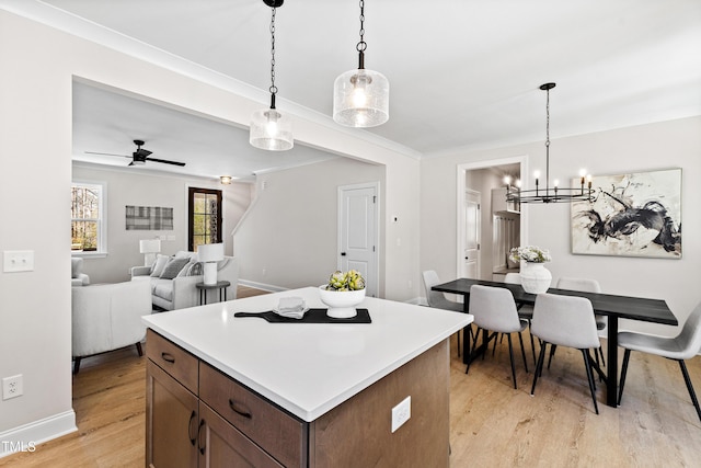 kitchen with light wood finished floors, light countertops, hanging light fixtures, and open floor plan