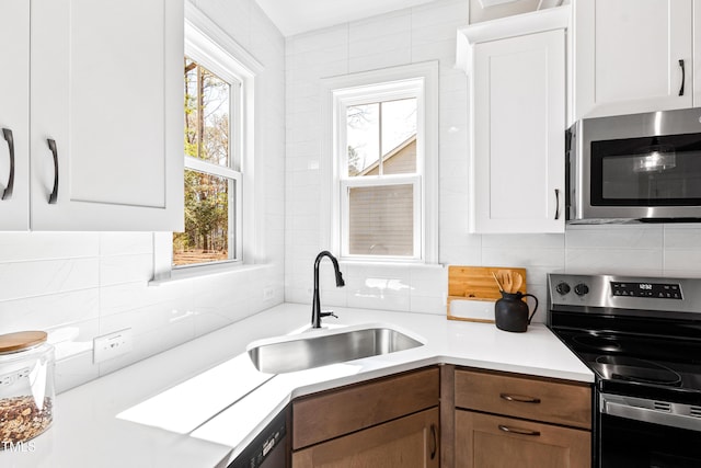 kitchen with stainless steel appliances, light countertops, and white cabinets