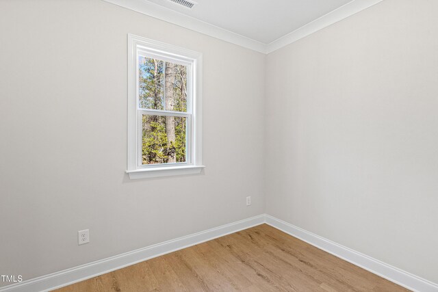 empty room with crown molding, baseboards, and wood finished floors