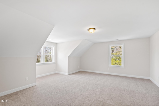 bonus room with baseboards, vaulted ceiling, visible vents, and light colored carpet