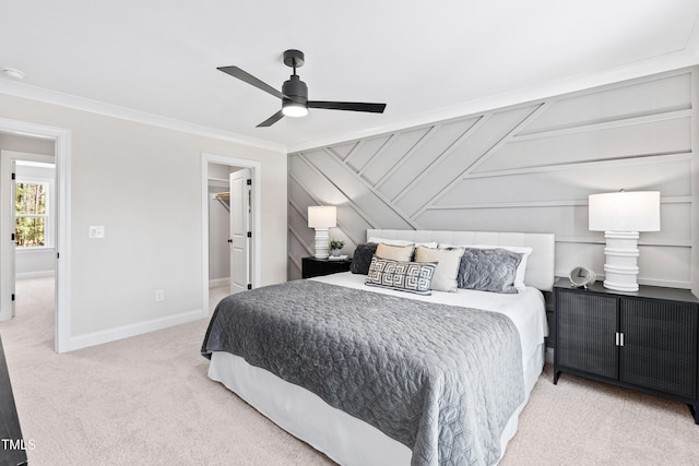 bedroom with ceiling fan, carpet floors, baseboards, ornamental molding, and a walk in closet