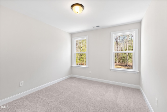 unfurnished room with carpet floors, visible vents, and baseboards