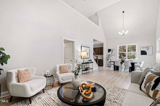 living room with an inviting chandelier, light hardwood / wood-style floors, and high vaulted ceiling