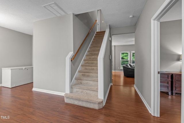 612 Quartz Dr, Durham, NC 27703 - stairs with wood finished floors, a textured ceiling, and baseboards