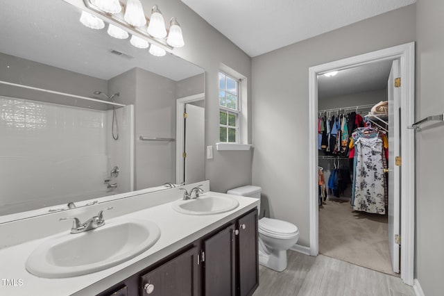 612 Quartz Dr, Durham, NC 27703 - full bathroom featuring wood finished floors, toilet, tub / shower combination, double vanity, and a walk in closet