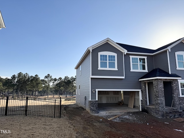 view of home's exterior featuring an attached garage, driveway, and fence