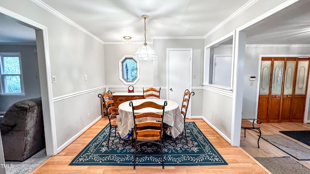dining area featuring light wood-style flooring, baseboards, and crown molding