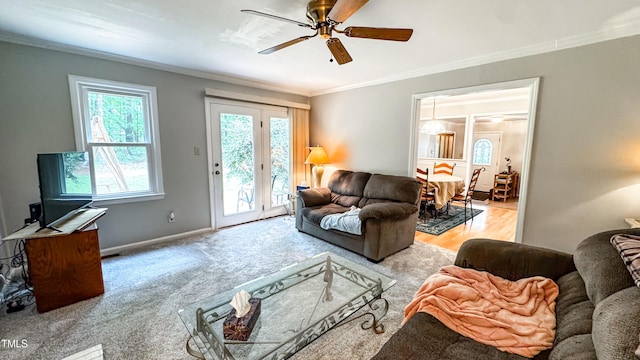 living area featuring crown molding, a ceiling fan, and baseboards