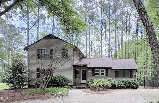 tri-level home featuring entry steps, fence, and a shingled roof