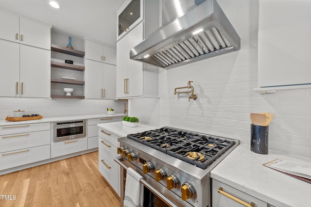 kitchen featuring tasteful backsplash, white cabinetry, high end stainless steel range, and wall chimney exhaust hood