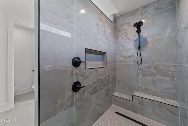 bathroom featuring tiled shower and toilet