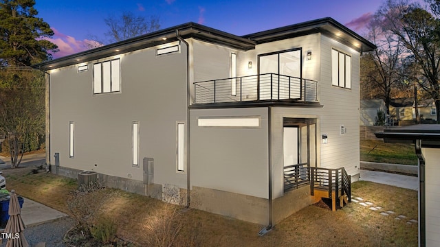 property exterior at dusk with a balcony and central air condition unit