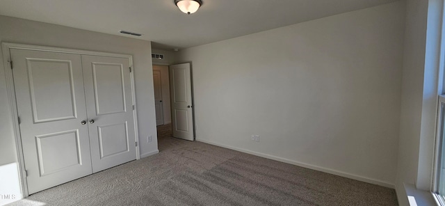 unfurnished bedroom with light colored carpet and a closet