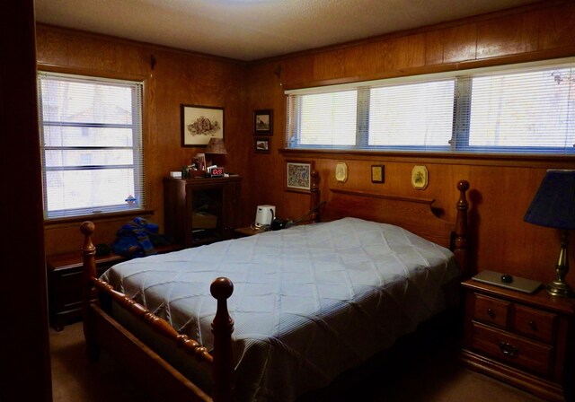 bedroom featuring wooden walls and carpet floors