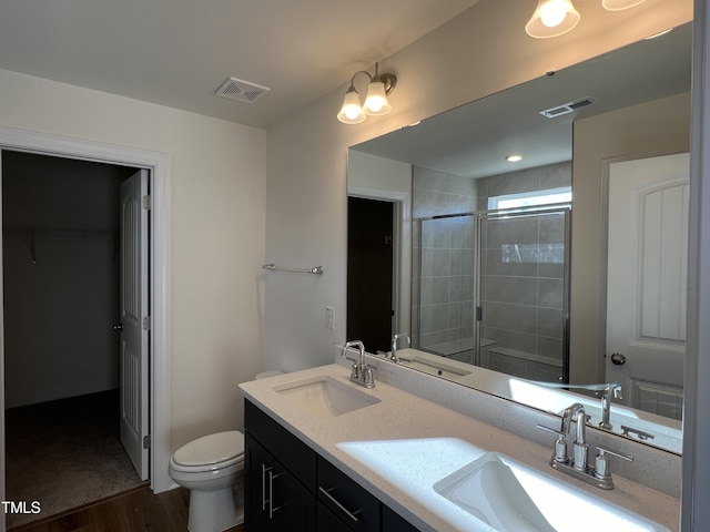 bathroom with vanity, wood-type flooring, a shower with shower door, and toilet