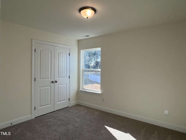 unfurnished bedroom featuring dark colored carpet and a closet