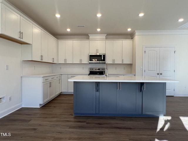 kitchen featuring dark hardwood / wood-style flooring, white cabinetry, stainless steel appliances, and a kitchen island with sink