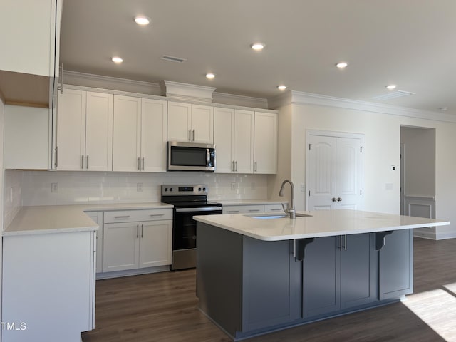 kitchen with stainless steel appliances, dark hardwood / wood-style floors, a center island with sink, and sink