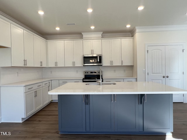 kitchen featuring dark hardwood / wood-style flooring, white cabinetry, stainless steel appliances, and an island with sink