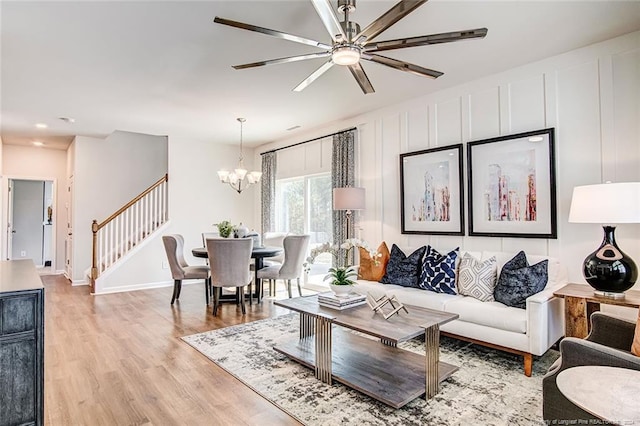 living room featuring ceiling fan with notable chandelier and light hardwood / wood-style floors