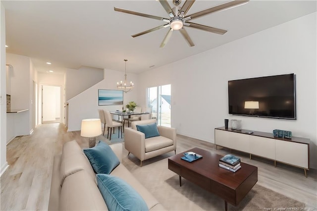 living room featuring ceiling fan with notable chandelier and light wood-type flooring