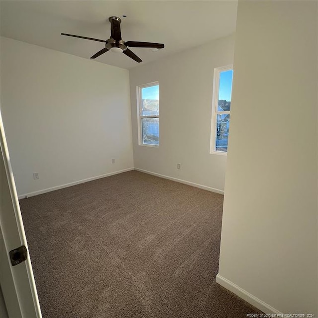 empty room featuring dark carpet and ceiling fan