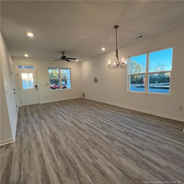 unfurnished living room with wood-type flooring and ceiling fan with notable chandelier