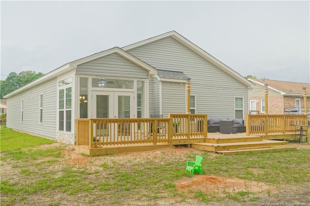back of house featuring a sunroom, a deck, and an outdoor living space