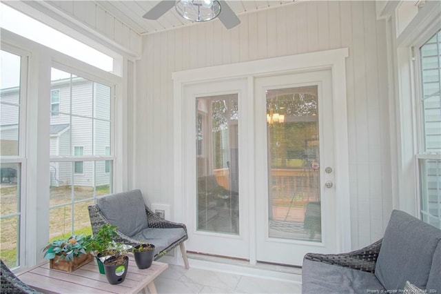 sunroom featuring marble finish floors, wooden walls, and french doors