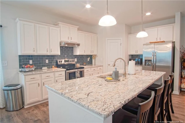 kitchen with stainless steel range with electric cooktop, a sink, under cabinet range hood, white cabinetry, and wood finished floors