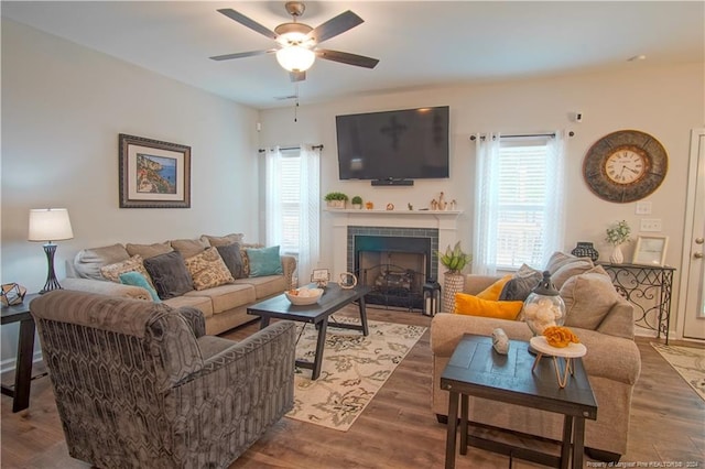 living area with plenty of natural light, ceiling fan, a tile fireplace, and wood finished floors