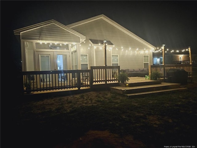 back of house at night featuring a deck