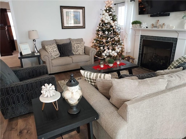 living area featuring healthy amount of natural light, wood finished floors, and a tile fireplace