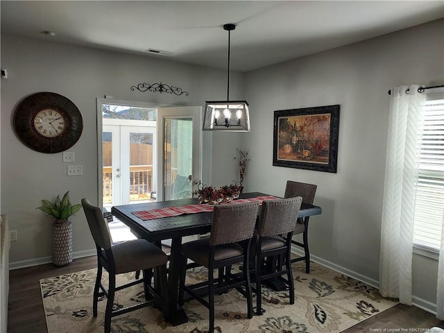 dining space featuring french doors, wood finished floors, a chandelier, and baseboards
