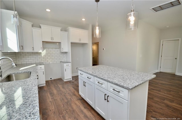 kitchen with white cabinets, a kitchen island, dark wood-type flooring, decorative light fixtures, and sink