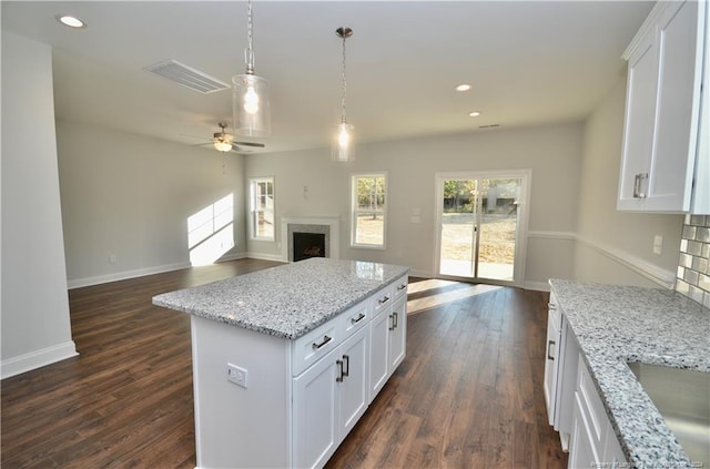 kitchen featuring a kitchen island, white cabinets, dark hardwood / wood-style floors, and ceiling fan