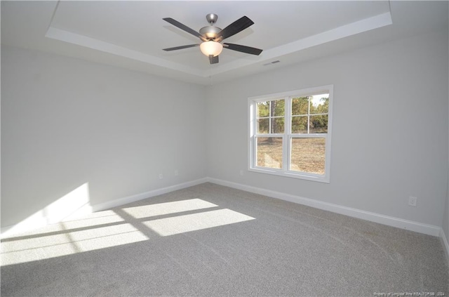 carpeted spare room with ceiling fan and a raised ceiling