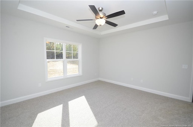 carpeted empty room with ceiling fan and a raised ceiling