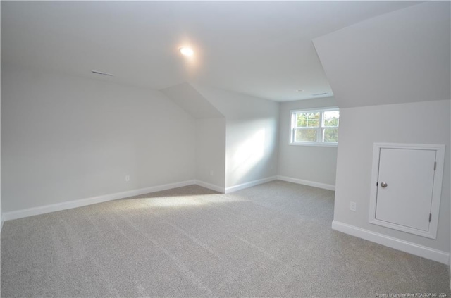 bonus room with vaulted ceiling and light carpet